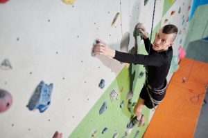 Image shows a man with limb difference climbing an indoor climbing wall.