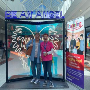 Sefton Foster Carer Ginny and Cllr Mhairi Doyle, Cabinet Member for Children's Social Care standing in front of neon angel wings