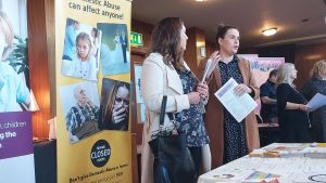 People holding leaflets from a stall about domestic abuse.