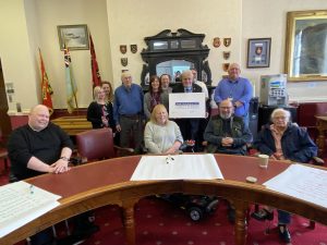 Those in attendance to sign the Disability Impact Pledge. A group sat around a table, holding the signed pledge.